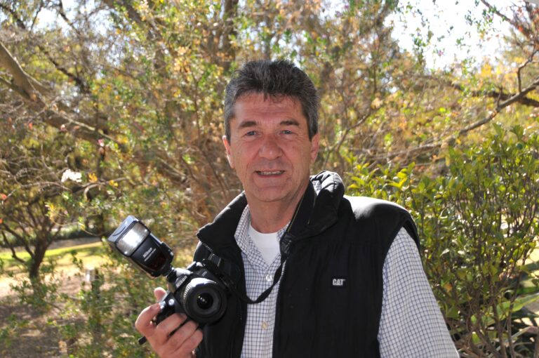 Man holding DSLR camera outdoors in park